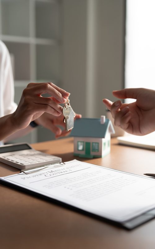 Client taking keys from real estate agent during meeting after signing rental lease contract or sale