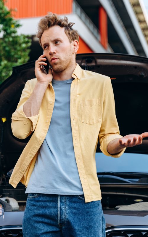 Handsome man making a telephone call to fix the car.